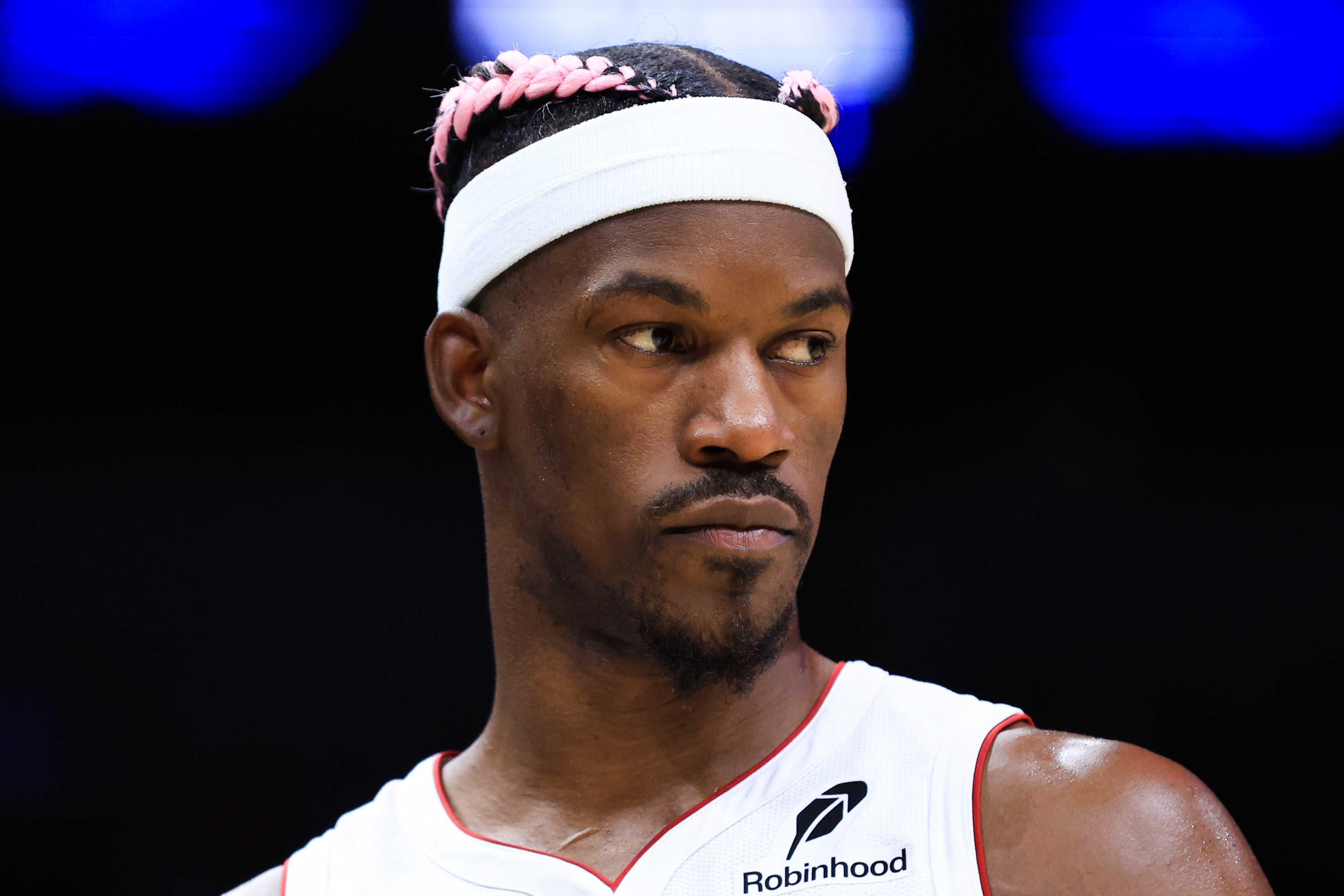 Jimmy Butler wearing a white headband and basketball jersey, looking to the side.